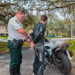 Motorcyclist being handcuffed by a police officer.