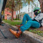 Motorcyclist leaned against a tree resting.